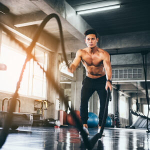 Men with battle rope in functional training fitness gym
